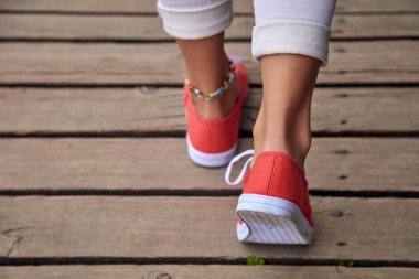 Kırmızı ayakkabılı bir kadın ve tahta panolarda beyaz bir kot..