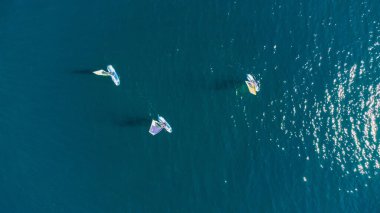Mavi okyanus sularındaki rüzgar sörfçülerinin insansız hava görüntüsü..