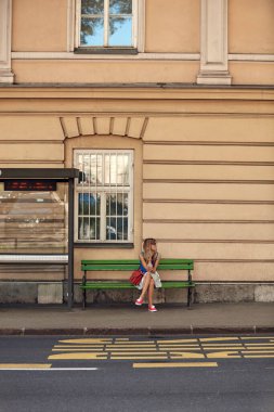 Beyaz bir kadın istasyonda toplu taşıma için bekliyor..