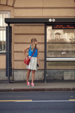 Beyaz bir kadın istasyonda toplu taşıma için bekliyor..