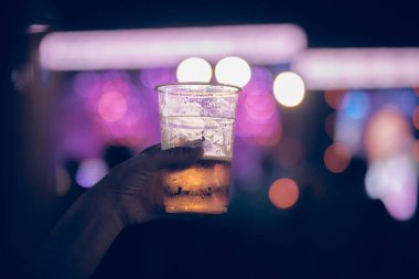 Bir müzik festivalinde elinde soğuk bira bardağı tutan biri..