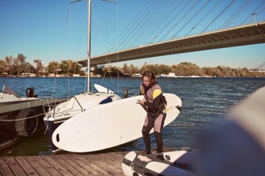 Rüzgar sörfçüsü nehirde rüzgarlı bir günde sörf yapıyor..