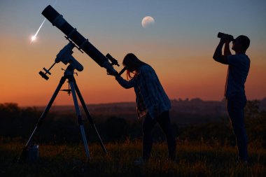Çift, astronomik bir teleskopla yıldızlara, gezegenlere, ay tutulmasına ve meteor yağmuruna bakıyor..