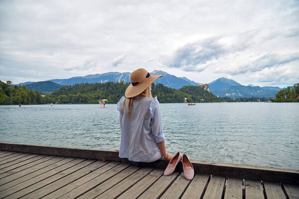 Young adult tourist woman enjoying barefeet on a lake wooden pier.