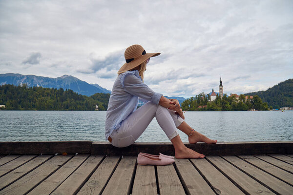 Young adult tourist woman enjoying barefeet on a lake wooden pier.