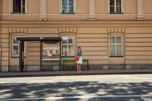 Beyaz bir kadın istasyonda toplu taşıma için bekliyor..