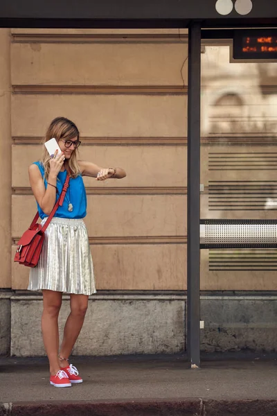 Beyaz bir kadın istasyonda toplu taşıma için bekliyor..