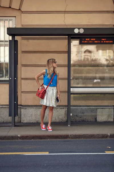 Beyaz bir kadın istasyonda toplu taşıma için bekliyor..