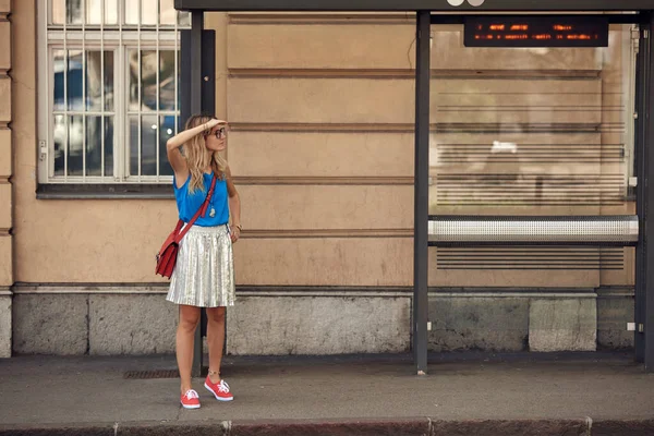 Beyaz bir kadın istasyonda toplu taşıma için bekliyor..