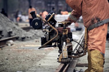 Çelik tren rayları için makine kullanan inşaat işçisi.