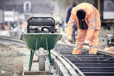 Çelik tren rayları için makine kullanan inşaat işçisi.