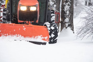 Soğuk bir günde traktör şehir parkı patikalarını temizliyor.
