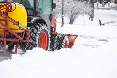 Soğuk bir günde traktör şehir parkı patikalarını temizliyor.