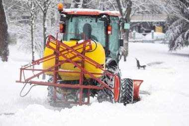 Soğuk bir günde traktör şehir parkı patikalarını temizliyor.