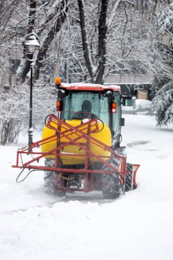 Soğuk bir günde traktör şehir parkı patikalarını temizliyor.
