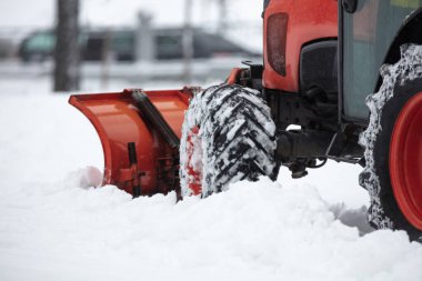 Soğuk bir günde traktör şehir parkı patikalarını temizliyor.