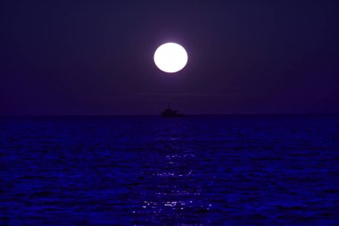 Büyük gün batımı okyanus ufkunda bir balıkçı teknesinin silüetiyle..