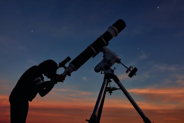 带着天文望远镜的女孩在暮色的天空下凝视着星星 — 图库照片