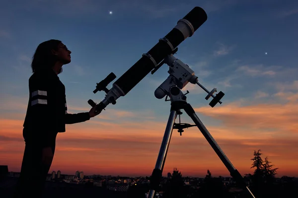 薄暗い空の下で天体望遠鏡の星を見る少女 — ストック写真