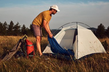 Doğada kamp yapan, küçük çadırları açan ve paketleyen, dinlenme ve hobileri olan bir adam..