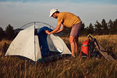 Doğada kamp yapan, küçük çadırları açan ve paketleyen, dinlenme ve hobileri olan bir adam..