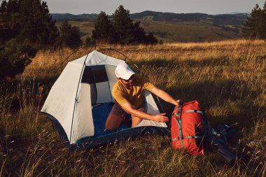 Doğada kamp yapan, küçük çadırları açan ve paketleyen, dinlenme ve hobileri olan bir adam..