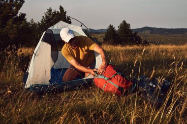 Doğada kamp yapan, küçük çadırları açan ve paketleyen, dinlenme ve hobileri olan bir adam..