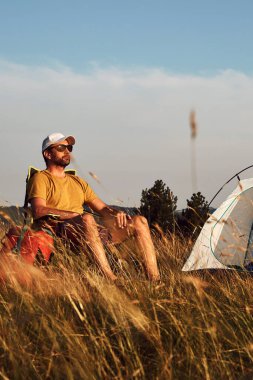 Doğada kamp yapan, küçük çadırları açan ve paketleyen, dinlenme ve hobileri olan bir adam..