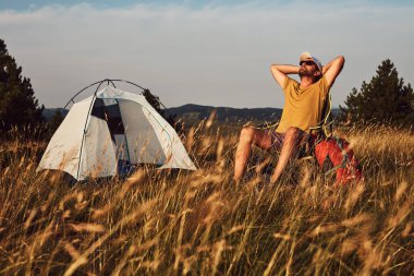 Doğada kamp yapan, küçük çadırları açan ve paketleyen, dinlenme ve hobileri olan bir adam..