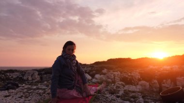 Gün batımında dışarıda yoga yapan bir kadın..