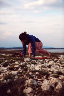 Gün batımında dışarıda yoga yapan bir kadın..
