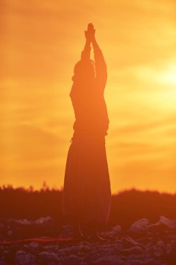 Gün batımında dışarıda yoga yapan bir kadın..