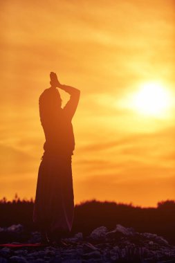 Gün batımında dışarıda yoga yapan bir kadın..
