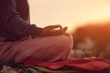 Gün batımında dışarıda yoga yapan bir kadın..