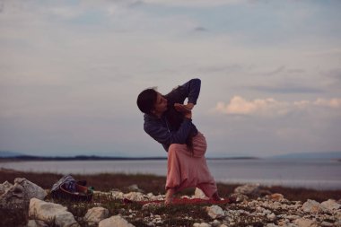 Gün batımında dışarıda yoga yapan bir kadın..