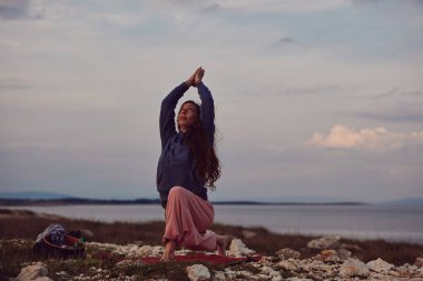 Gün batımında dışarıda yoga yapan bir kadın..