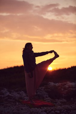 Gün batımında dışarıda yoga yapan bir kadın..