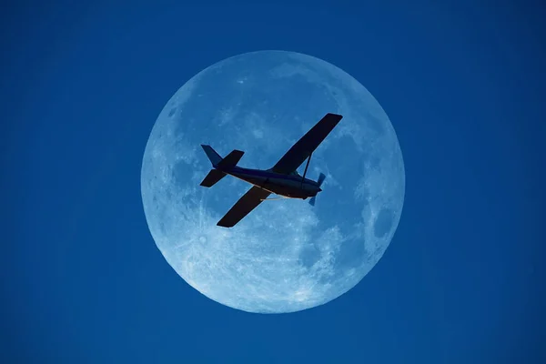 Airplane flying over the full Moon disk.