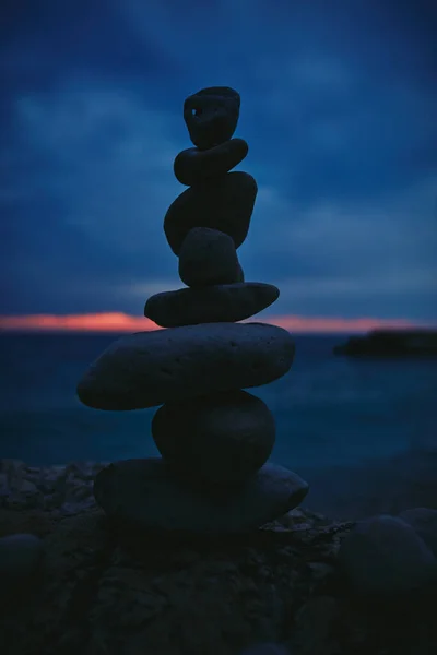 Silhouette of balanced zen stones on the ocean beach ant sunset sunrise time.