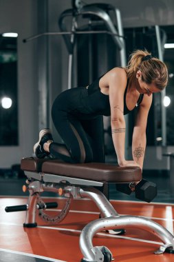 Spor salonunda küçük ağırlıklarla çalışan güzel bir kadın. Güzel vücutlu yetişkin bir kadın..