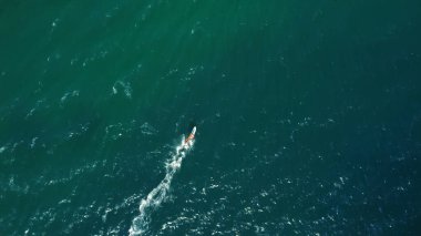 Mavi deniz dalgalarının tadını çıkaran rüzgar sörfçülerinin hava aracı görüntüsü.