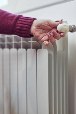 Soğuk bir kış gününde ısınan kadın, enerji ve gaz krizi, soğuk oda, ısıtma sorunları.