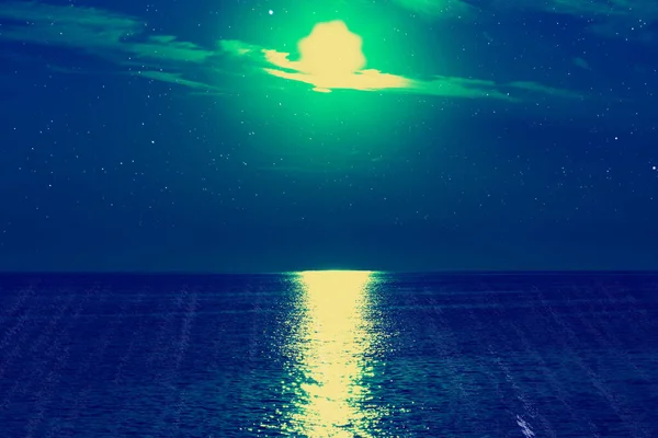 Moon with starry skies above ocean horizon.