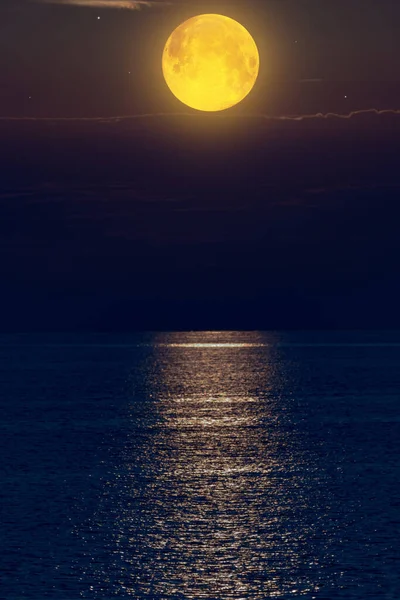 Moon with starry skies above ocean horizon.