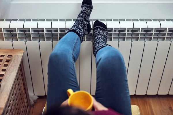 Γυναίκα Θέρμανση Πόδια Μια Κρύα Χειμωνιάτικη Μέρα Κρατώντας Φλιτζάνι Καφέ — Φωτογραφία Αρχείου