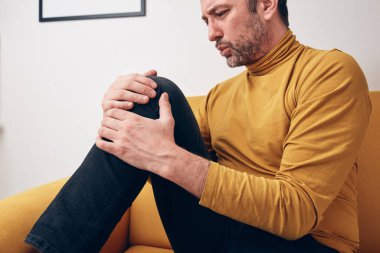 Diz ağrısı, çıkık, uyuşukluk, kramp ve diğer eklem sorunları olan yetişkin bir erkek..