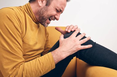 Diz ağrısı, çıkık, uyuşukluk, kramp ve diğer eklem sorunları olan yetişkin bir erkek..