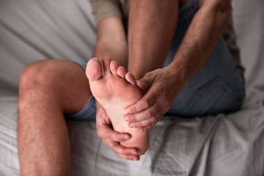 Ayak ağrısı, çıkık, uyuşukluk, kramp ve diğer eklem sorunları olan yetişkin bir erkek..