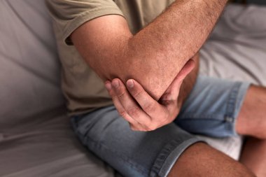 Dirseği, kolu ve bileği ağrıyan yetişkin bir adam..