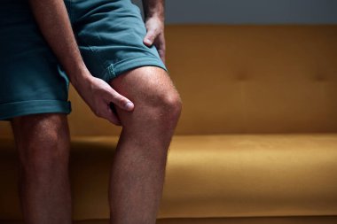 Diz ağrısı, çıkık, uyuşukluk, kramp ve diğer eklem sorunları olan yetişkin bir erkek..